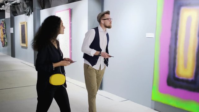 Visitors of exhibition of modern painting are listening comments by audio guide