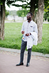 Young african american male doctor hold white coat on hand with a stethoscope posed outdoor.