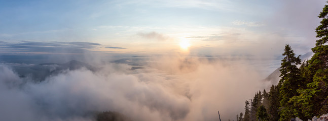 Beautiful Panoramic View of Canadian Mountain Landscape covered in clouds during a vibrant summer sunset. Taken on top of St Mark's Summit, West Vancouver, British Columbia, Canada.