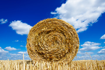 Straw bale with blue cloudy sky