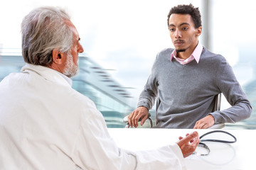 Fototapeta premium YongMale patient having consultation with senior male doctor in medical office.