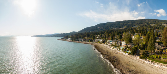 Aerial Panoramic View of a rocky beach in the modern city during a vibrant sunny day. Taken in West Vancouver, British Columbia, Canada.