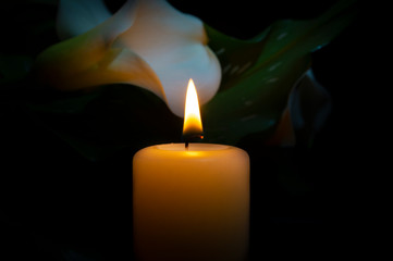 Close up of orange candle flame and lily flowers