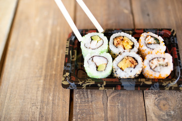 Tasty sushi rolls and laptop at wooden table. Food delivery. Workplace at home