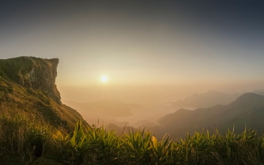 Mountain view misty morning of high cliff around with soft mist with yellow sun light background, sunrise at Phu Chi Fa (Phu Chee Fah), Chiang Rai, Thailand.