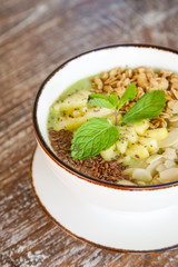 Delicious organic smoothie bowl garnished with pineapple, almond slices and granola, healthy raw vegan meal