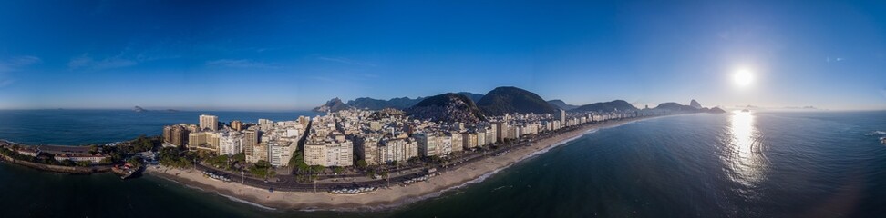 360 degree full panoramic aerial view of Rio de Janeiro with Copacabana beach and fort in the foreground and the wider cityscape in the background against a colourful clear blue sky at sunrise