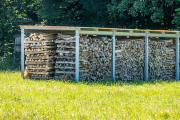 Brennholz Lager abgedeckt auf Wiese im Sommer