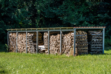 Brennholz Lager abgedeckt auf Wiese im Sommer