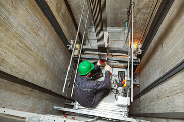 lift machinist repairing elevator in lift shaft - obrazy, fototapety, plakaty