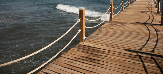 Obraz premium Scene at Tropical Beach Resort with wooden pier and rope
