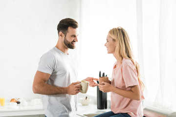 beautiful couple with cups of coffee during breakfast at kitchen