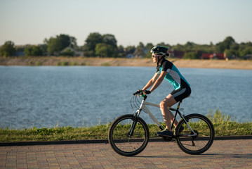 Obraz premium Woman on bike at the lake water background in the park
