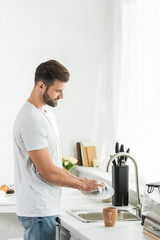 handsome man washing dishes at kitchen in morning