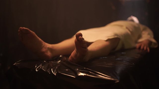 Dead male body laid out on an autopsy table comes back to life