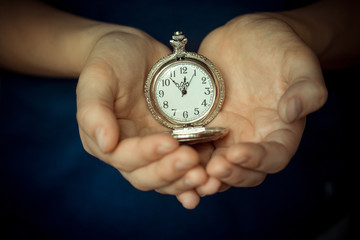In the children's palms the old clock. Conceptual photography. The time is 11.55. Five minutes to...