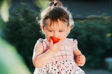 A little girl eating a tomato. Very nice kontrova lights in the garden