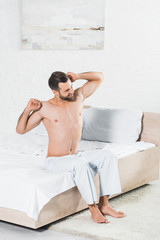 handsome man stretching on bed during morning in bedroom
