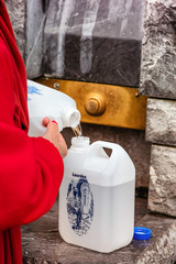 Pilgrim filling holy water near the grotto of Lourde