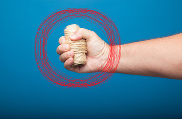 Rollo de cuerda cogido y sujetado por el puño de una mano derecha. Mano derecha coje un rollo de...