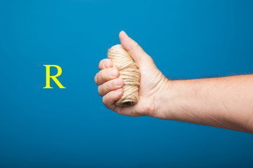 Rollo de cuerda cogido y sujetado por el puño de una mano derecha. Mano derecha coje un rollo de...