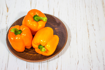Bulgarian orange pepper on a wooden white background.