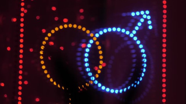 Bright neon sign of gender symbols at the entrance to the sex shop. Night time. Close up.