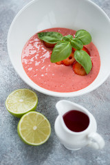 Closeup of cold summer soup made of fresh strawberries and served in a white bowl, vertical shot, elevated view