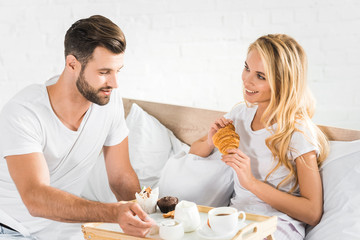 beautiful couple having breakfast in bed in morning