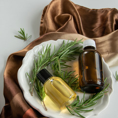 Bottles with rosemary essential oil. Herbal cosmetic treatment products.