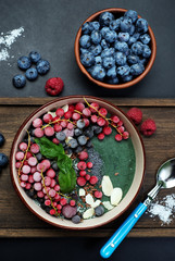 Healthy organic frozen smoothie with spirulina and banana, decorated with berries, seeds and coconut flakes. Fashionable and healthy food from natural ingredients. Super food