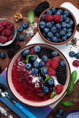 Healthy organic smoothie with blackberry and banana, decorated with raspberry, blueberry and coconut chips. Fashionable and healthy food from natural ingredients. Super food