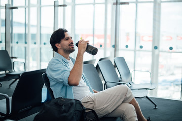The guy at the airport waiting for departure, drinking water.