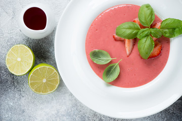 Top view of summer soup with fresh strawberries served in a white plate, closeup
