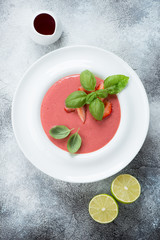 White plate with strawberry cream-soup, view from above on a grey stone background, studio shot