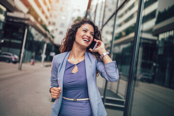 Portrait Of Beautiful Smiling Female In Fashion Office Clothes Talking On Phone While Standing Outdoors
