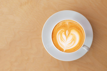 a cup of hot latte coffee on wooden table in coffee shop