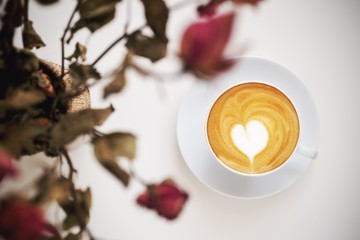 a cup of hot latte coffee on white table in coffee shop