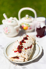 Meringue roll with fresh berries - cherry and red currant - on white plate