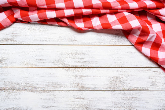 a checked gingham picnic tablecloth on old wooden table top view