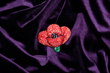 Designer brooch made of handmade jewelry in the shape of flower isolated on lilac background.