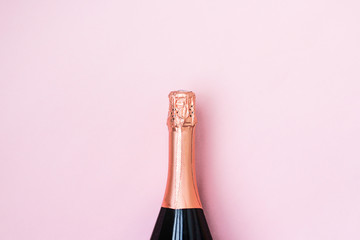 bottle of sparkling wine on pink background. closed bottle of champagne to celebrate the holidays.