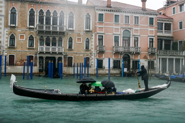 Fototapeta na wymiar Gondolier on gondola on the Grand Canal in Venice, Italy. April 2012 Rainy day