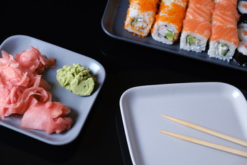 Sushi roll with seafood and soy sauce, wasabi and ginger. Sushi roll with salmon on a gray plate and black table
