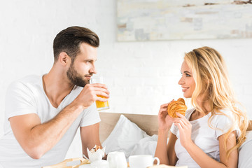 Obraz na płótnie Canvas beautiful couple having breakfast in bed in morning