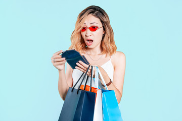 Frustrated and surprised Asian girl looks at an empty wallet after shopping. Concept of family...
