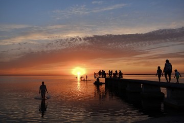 silhouette of people on pier at sunset