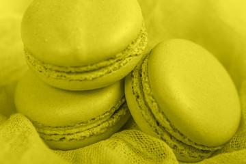 Delicious french dessert. Three gentle soft pastel yellow cakes  macaron or macaroon on airy fabric,
