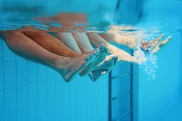  legs of caucasian family (friends) underwater in swimming pool. Summer. Vacation, family and sport concept.