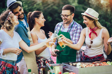 Young friends having fun grilling meat enjoying barbecue party.